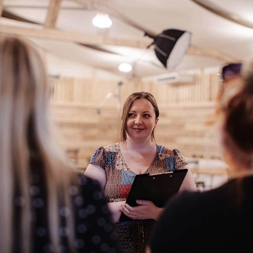 Emma Rees, owner of Little Rain Events, speaking with guests while holding a clipboard